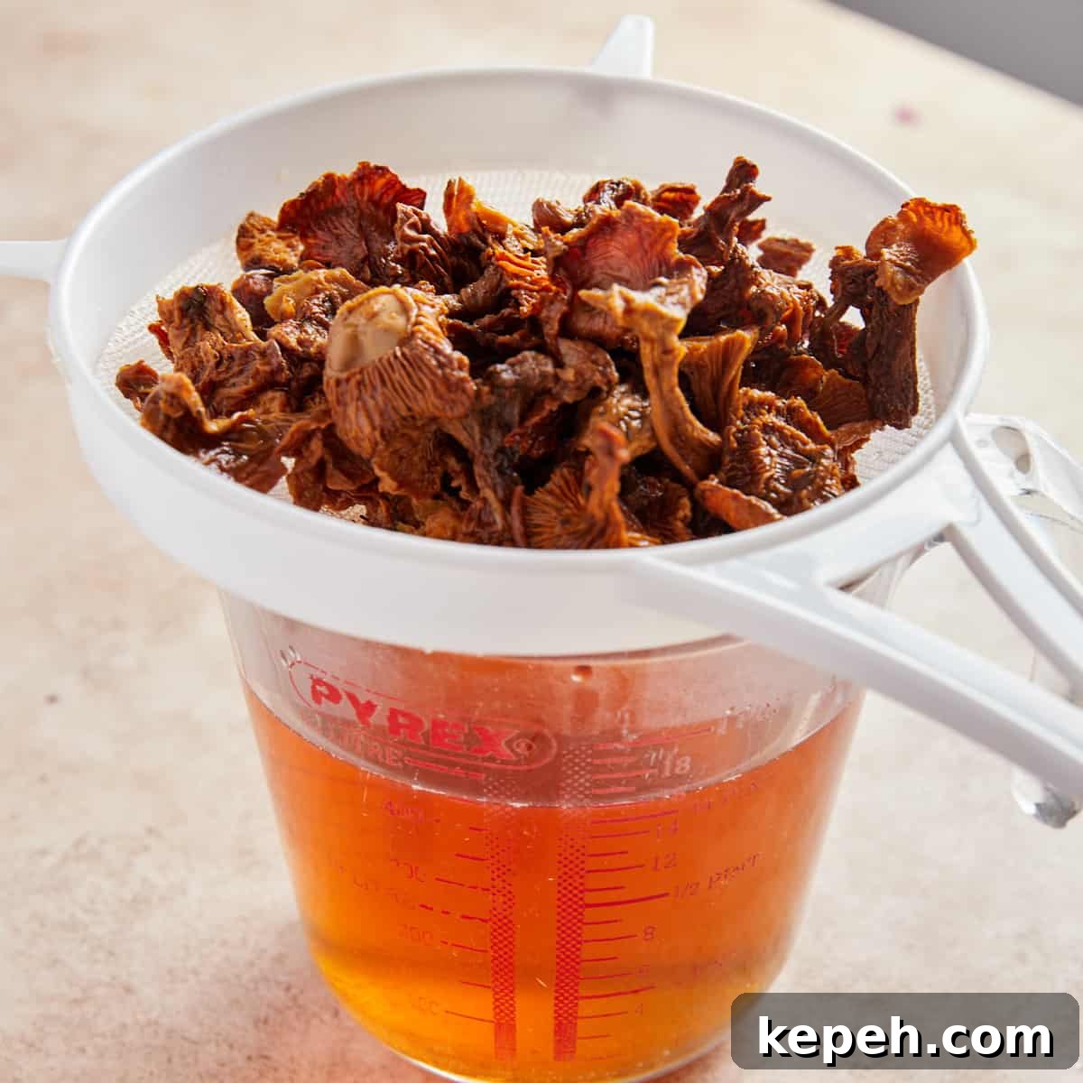 Photo showing the dried mushrooms being drained into a jug to retain the soaking water.
