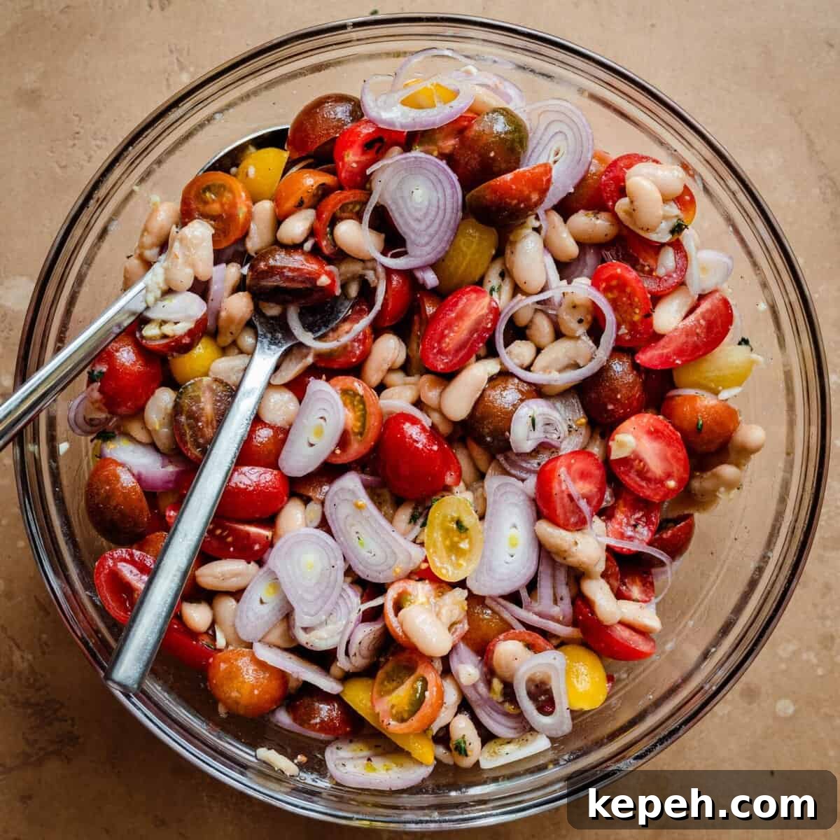 cherry tomato white bean shallot salad in glass bowl.