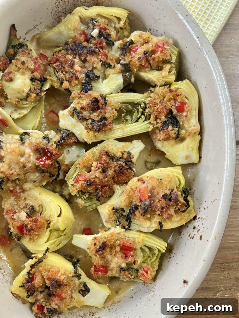 Finished, baked italian artichoke hearts oreganata in oval baking dish on yellow towel.