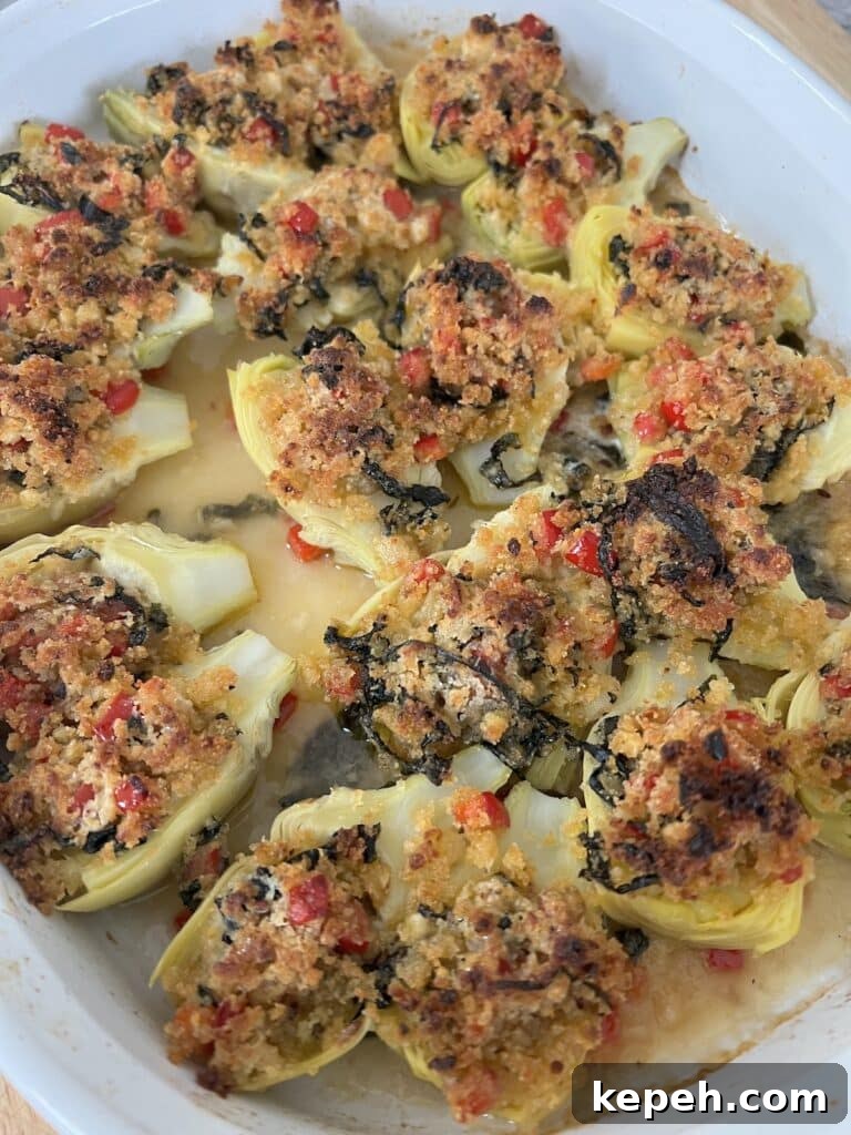 Finished, baked artichoke hearts in white baking dish.