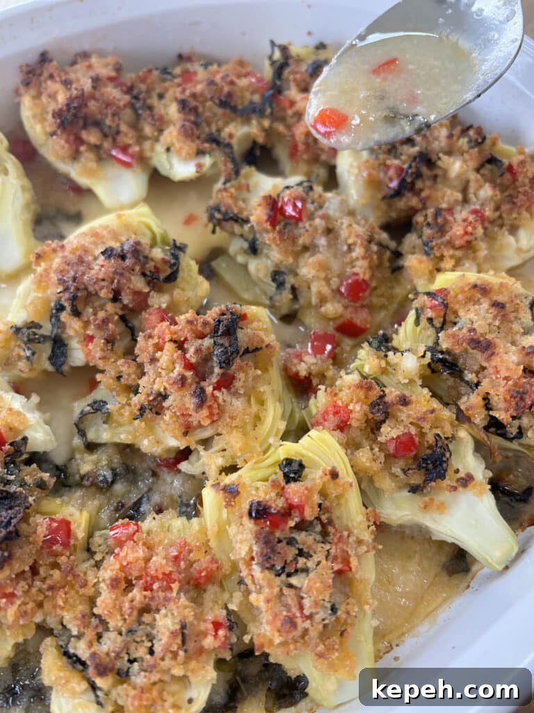 Drizzling some pan sauce over baked italian artichoke hearts.