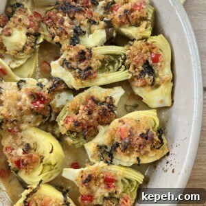 Finished, baked italian artichoke hearts oreganata in oval baking dish on yellow towel.