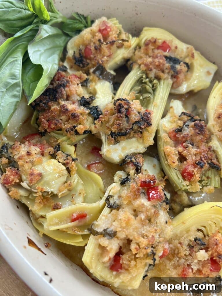 Roasted Italian artichoke hearts oreganata with lemon basil breadcrumbs in baking dish with basil garnish.