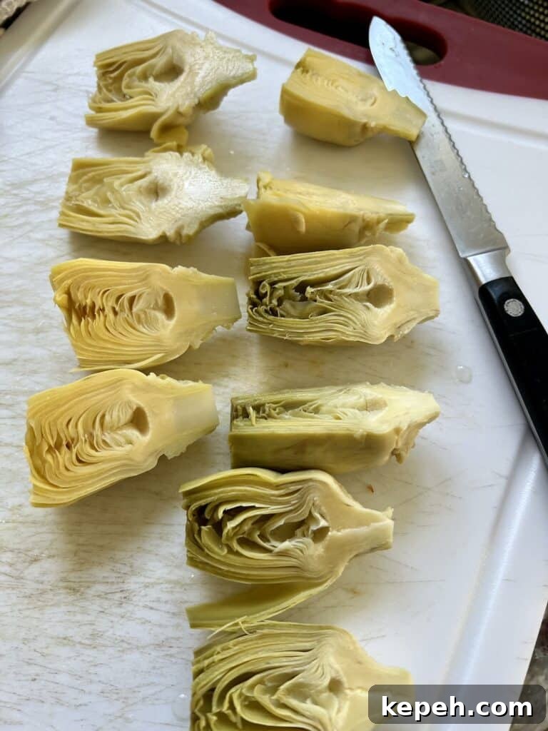 Cutting the artichoke hearts in half with serrated knife.