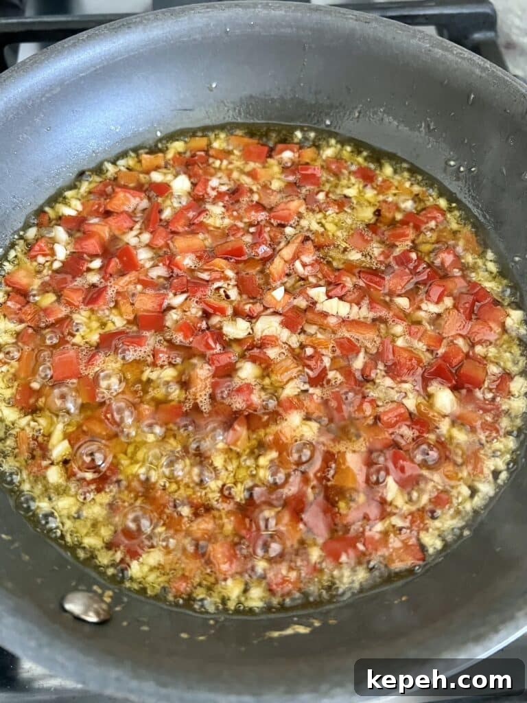 Sautéing chopped garlic, red bell peppers and crushed red pepper in olive oil in small skillet.