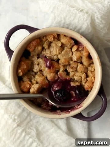 Single serve blueberry crisp in a ramekin with an oat topping.