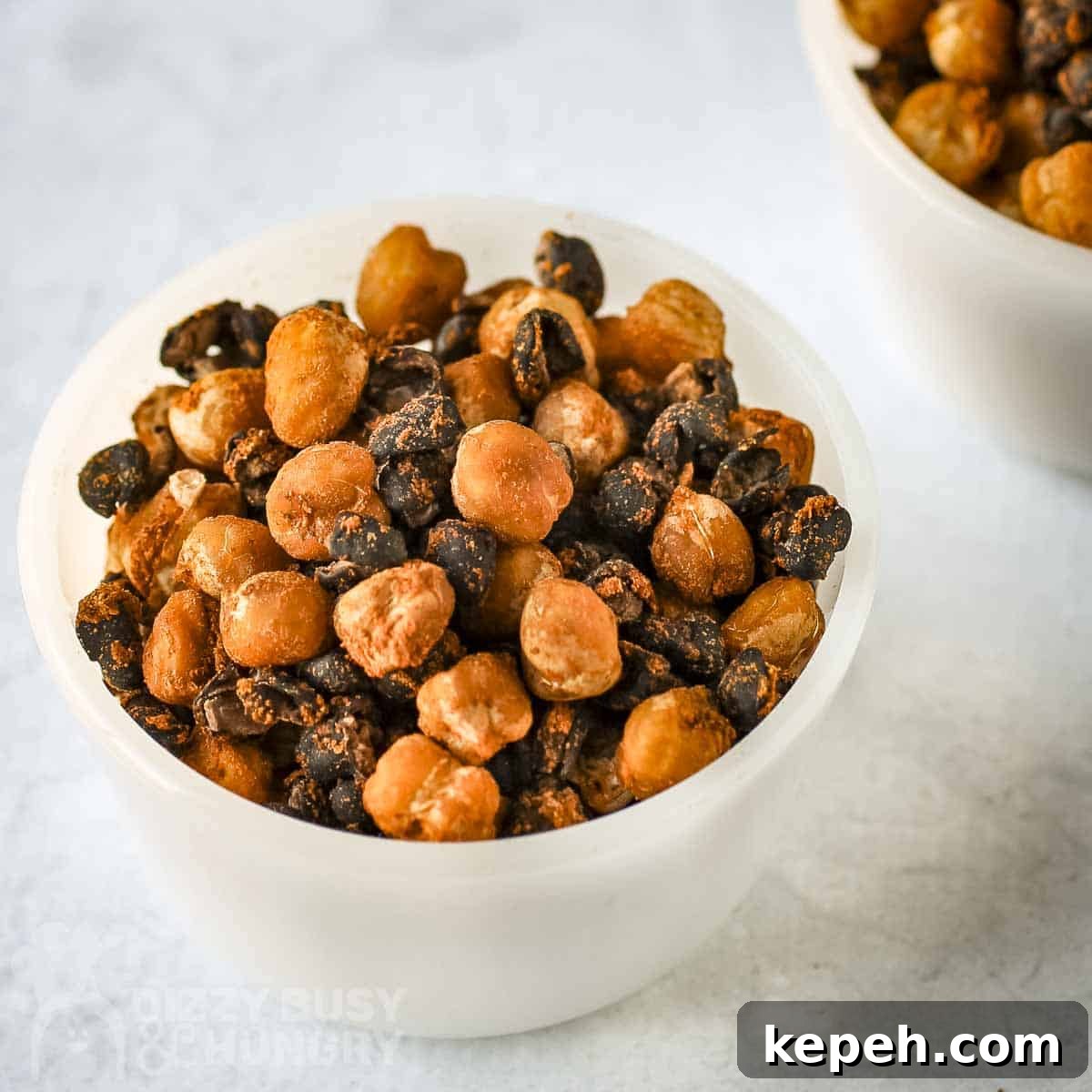 Close up angled shot of two white bowls of chickpeas and black beans.