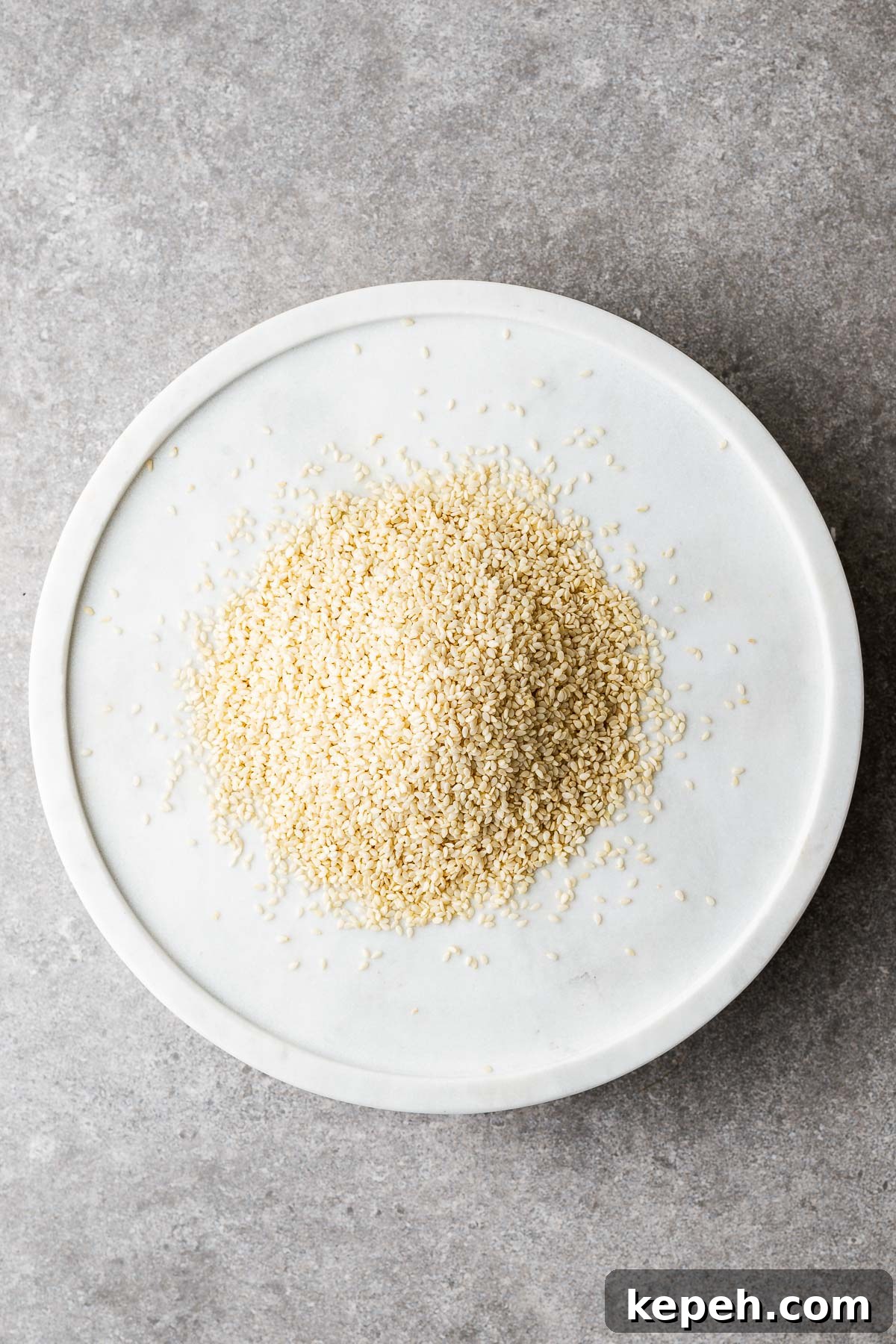 How to Toast Sesame Seeds on the Stove or in the Oven 3 A marble plate with raw sesame seeds. The sesame seeds are white and hulled.