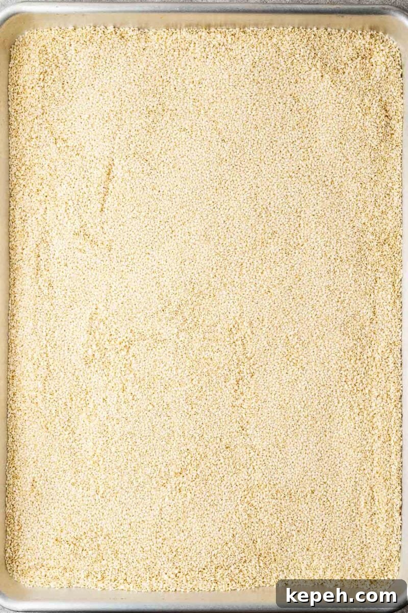 How to Toast Sesame Seeds on the Stove or in the Oven 4 Raw white sesame seeds on a sheet pan.