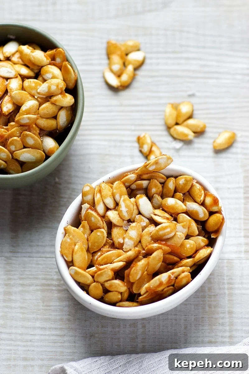 Salted Caramel Pumpkin Seeds Recipe — Crunchy Fall Snack 4 Salted Caramel Pumpkin Seeds in a green bowl and a white bowl and a white tea towel.