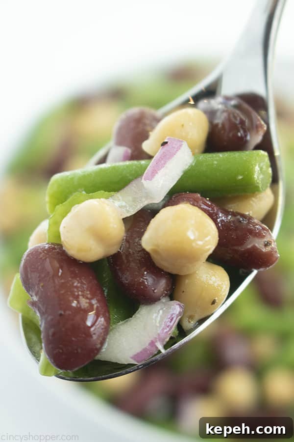 Classic Three-Bean Salad Recipe for Summer Potlucks 5 Three types of beans, celery, and red onion on a spoon