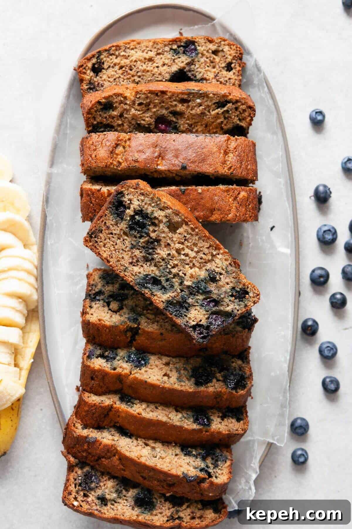 Sliced healthy blueberry banana bread showing moist texture and juicy blueberries in every slice.