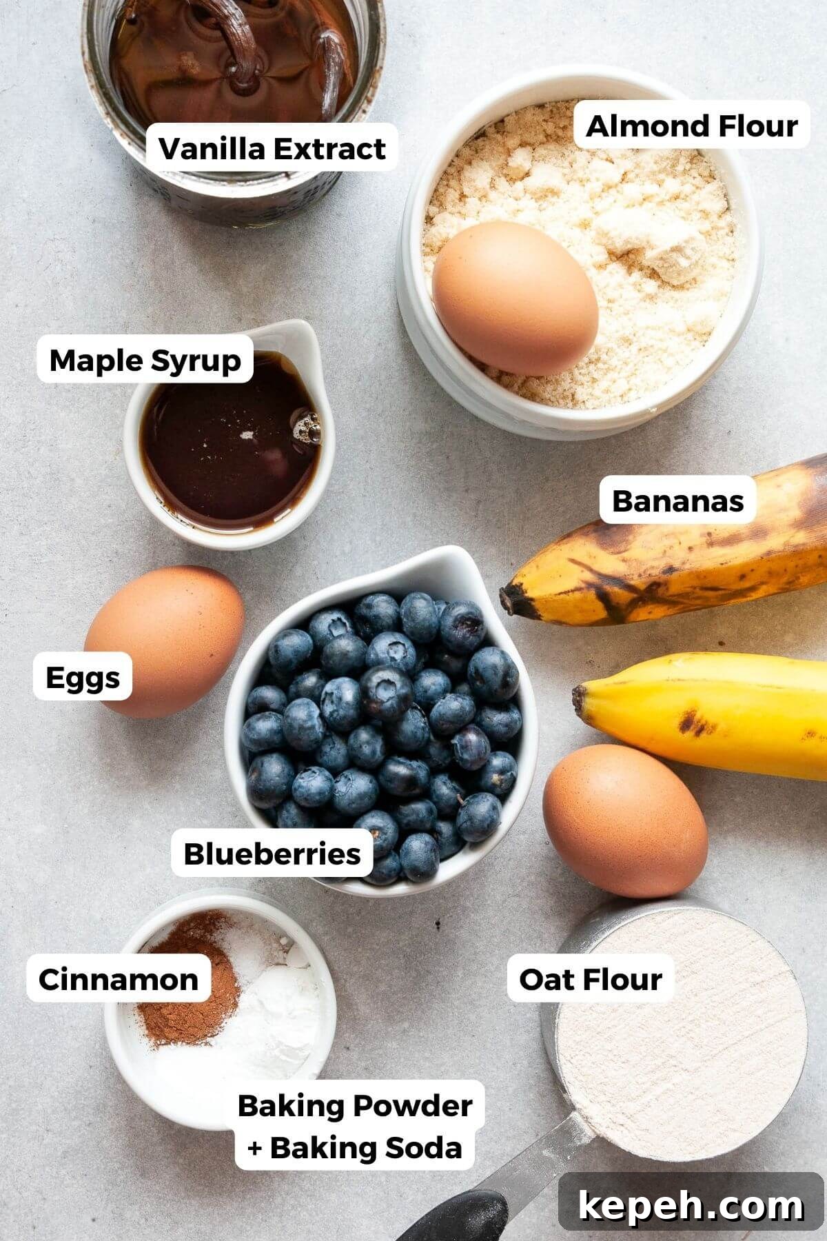Ingredients for healthy blueberry banana bread including almond flour, oat flour, ripe bananas, eggs, maple syrup, and fresh blueberries.
