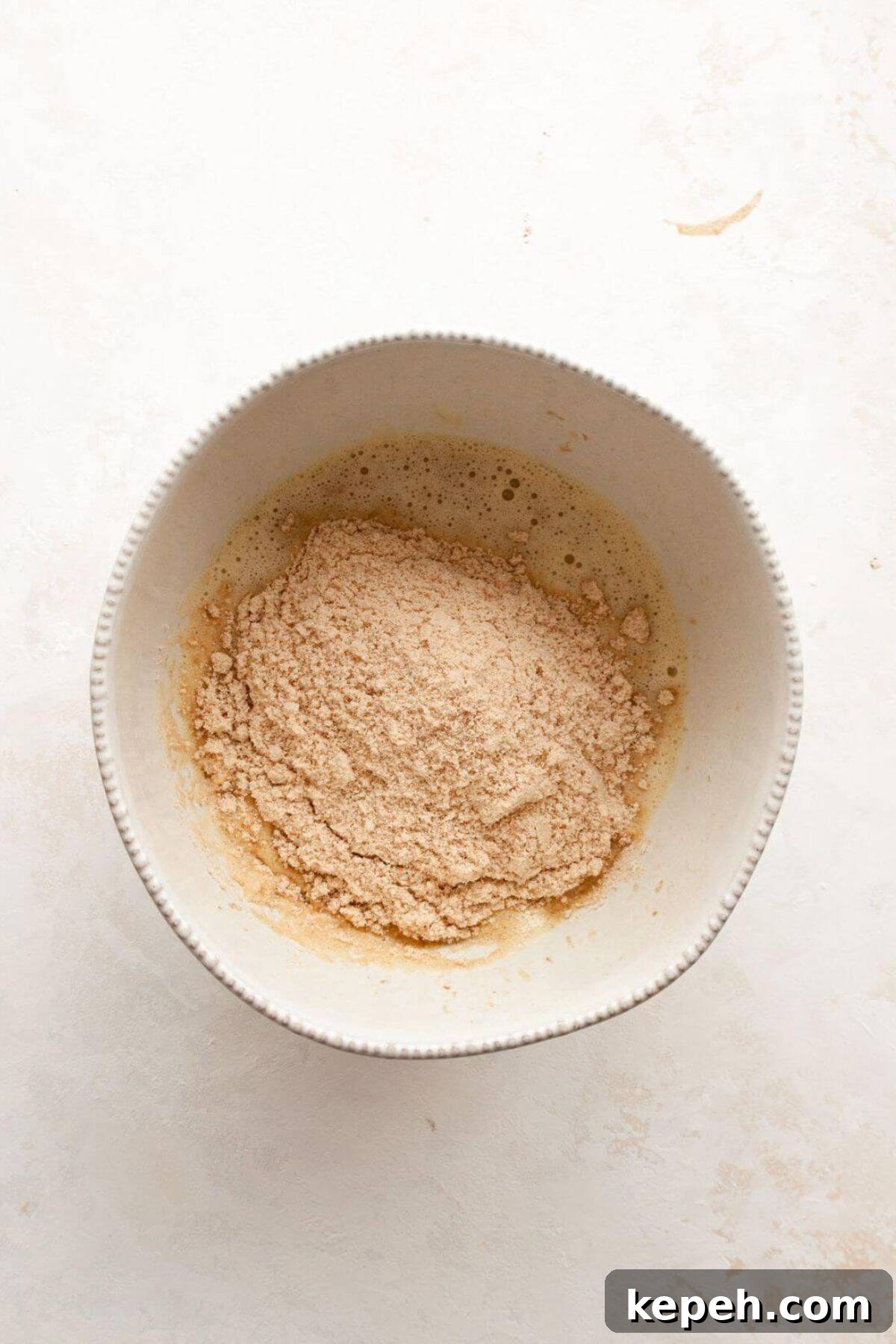 Mixing dry and wet ingredients together to form banana bread batter.
