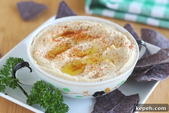 Creamy hummus in a bowl with tortilla chips.