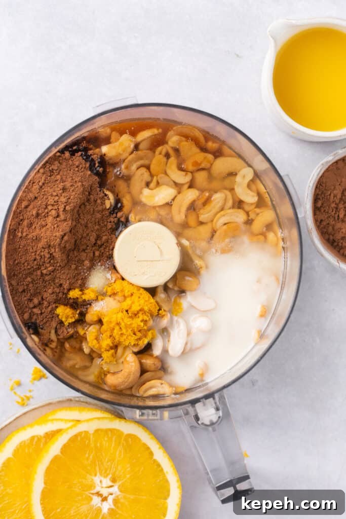 No-Bake Orange Chocolate Fudge Recipe: Zesty Cocoa Treat 4 A food processor filled with cashews, orange juice, coconut butter, cocoa powder and maple syrup.
