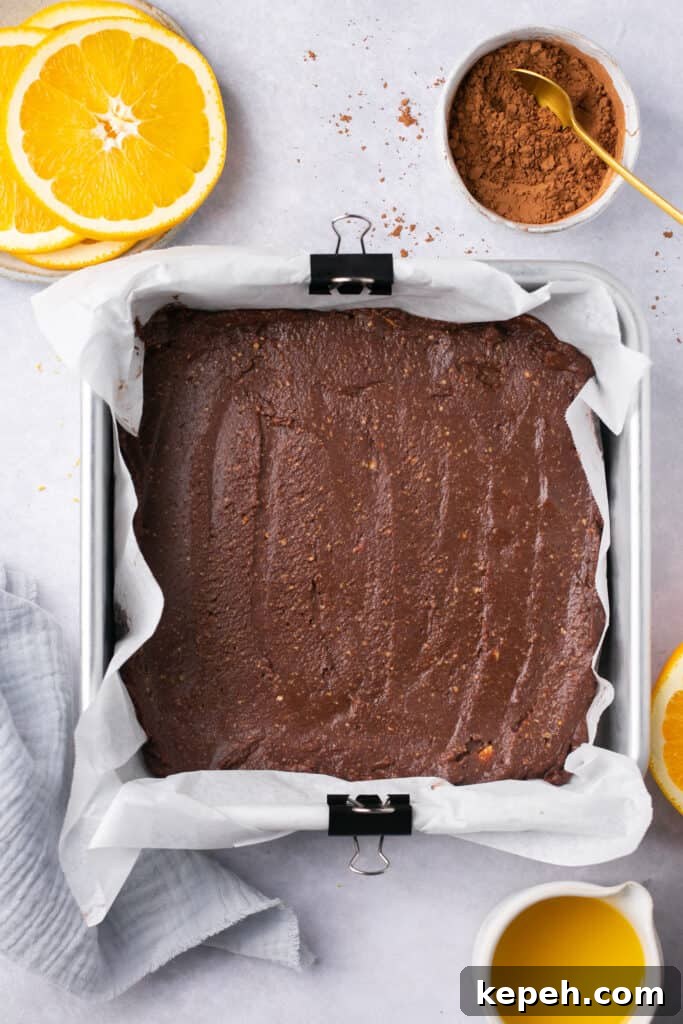 No-Bake Orange Chocolate Fudge Recipe: Zesty Cocoa Treat 7 A square pan lined with parchment paper with chocolate fudge in it.