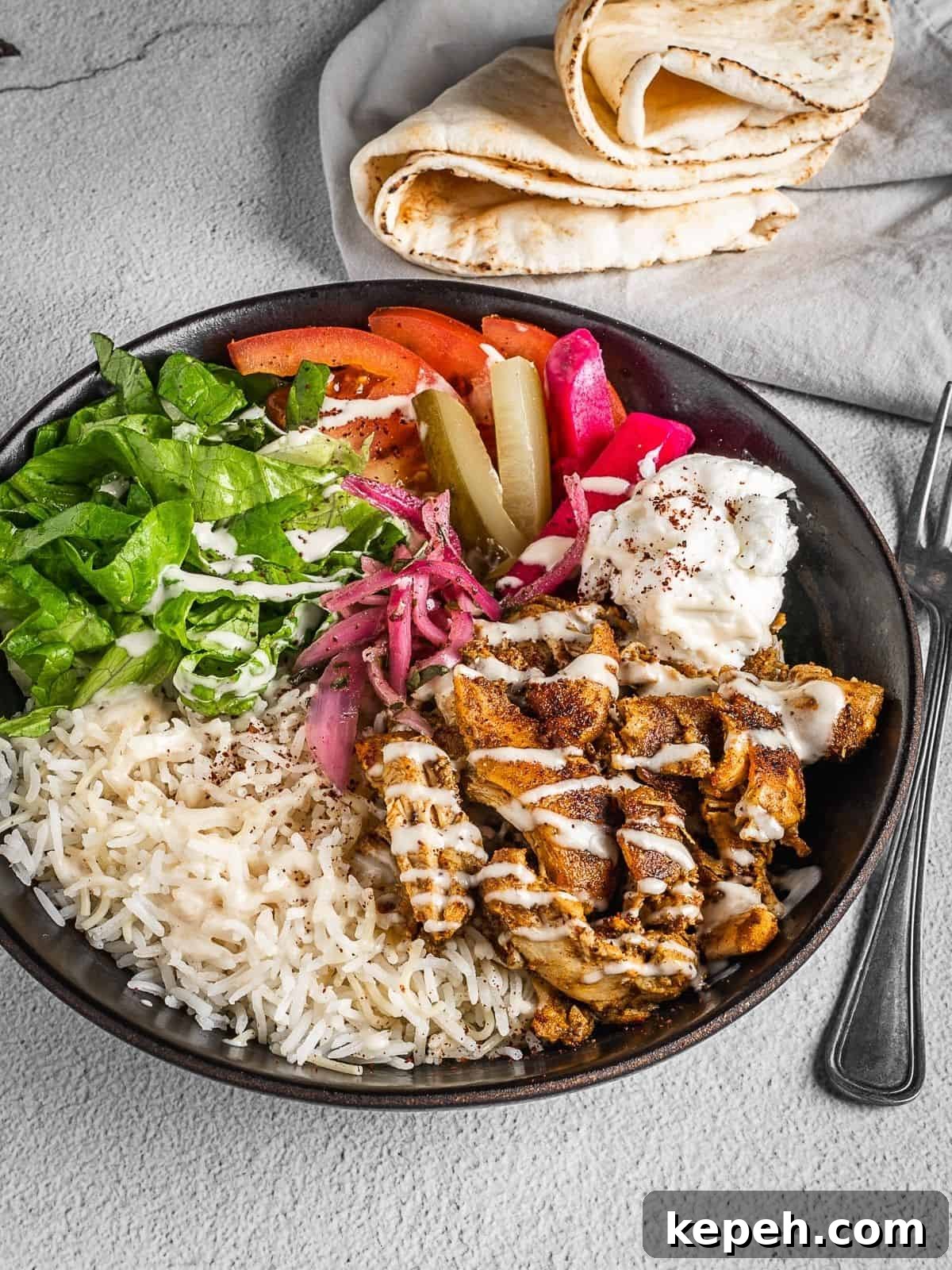 Lebanese Chicken Shawarma Recipe: Wraps or Bowls Made at Home 12 Lebanese chicken shawarma bowl with rice, lettuce, chicken, tomatoes, garlic sauce and pickles.