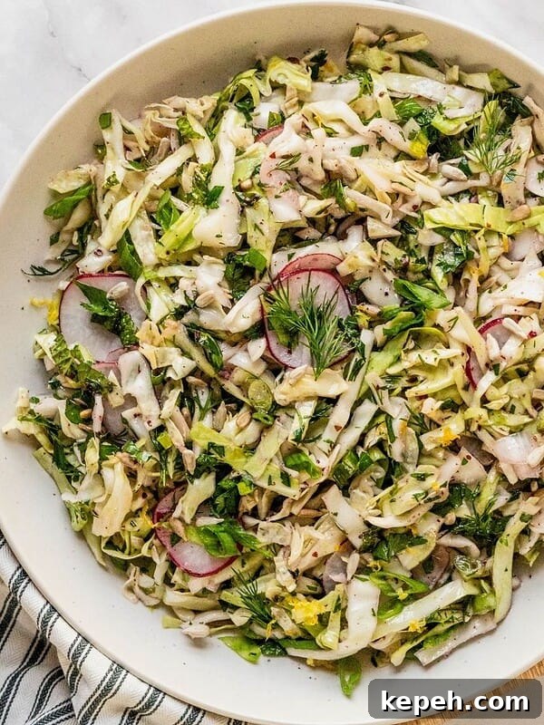 No mayo coleslaw with radish, fresh herbs in a lemon sumac dressing in a bowl.