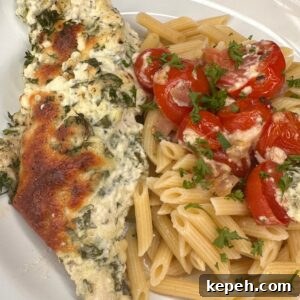Creamy Boursin Chicken Bake Recipe for Weeknight Dinners 3 A plate with baked chicken topped with herbs and cheese, served alongside penne pasta mixed with cherry tomatoes and parsley.