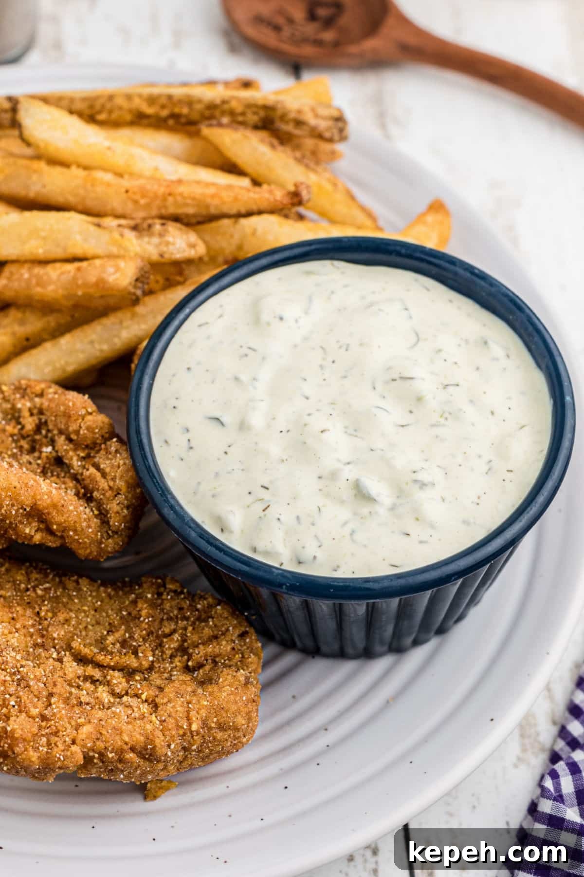 an overhead view of a dish of tartar sauce with some fish on the side.