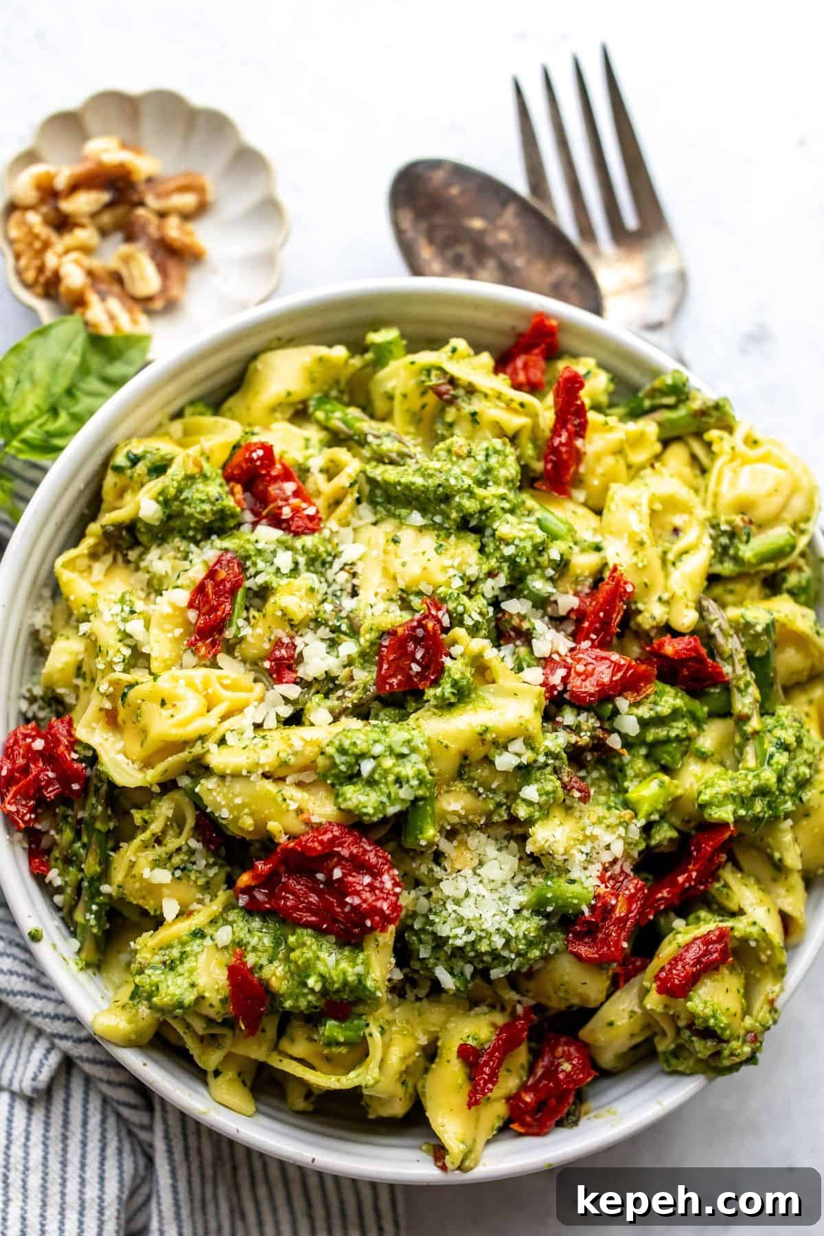 Tortellini with pesto in a white bowl up close.