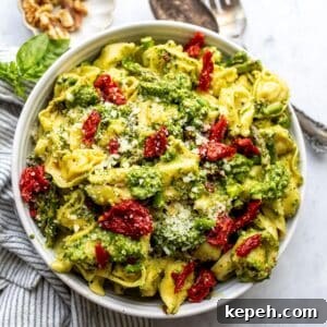 Tortellini with pesto in a white bowl up close.