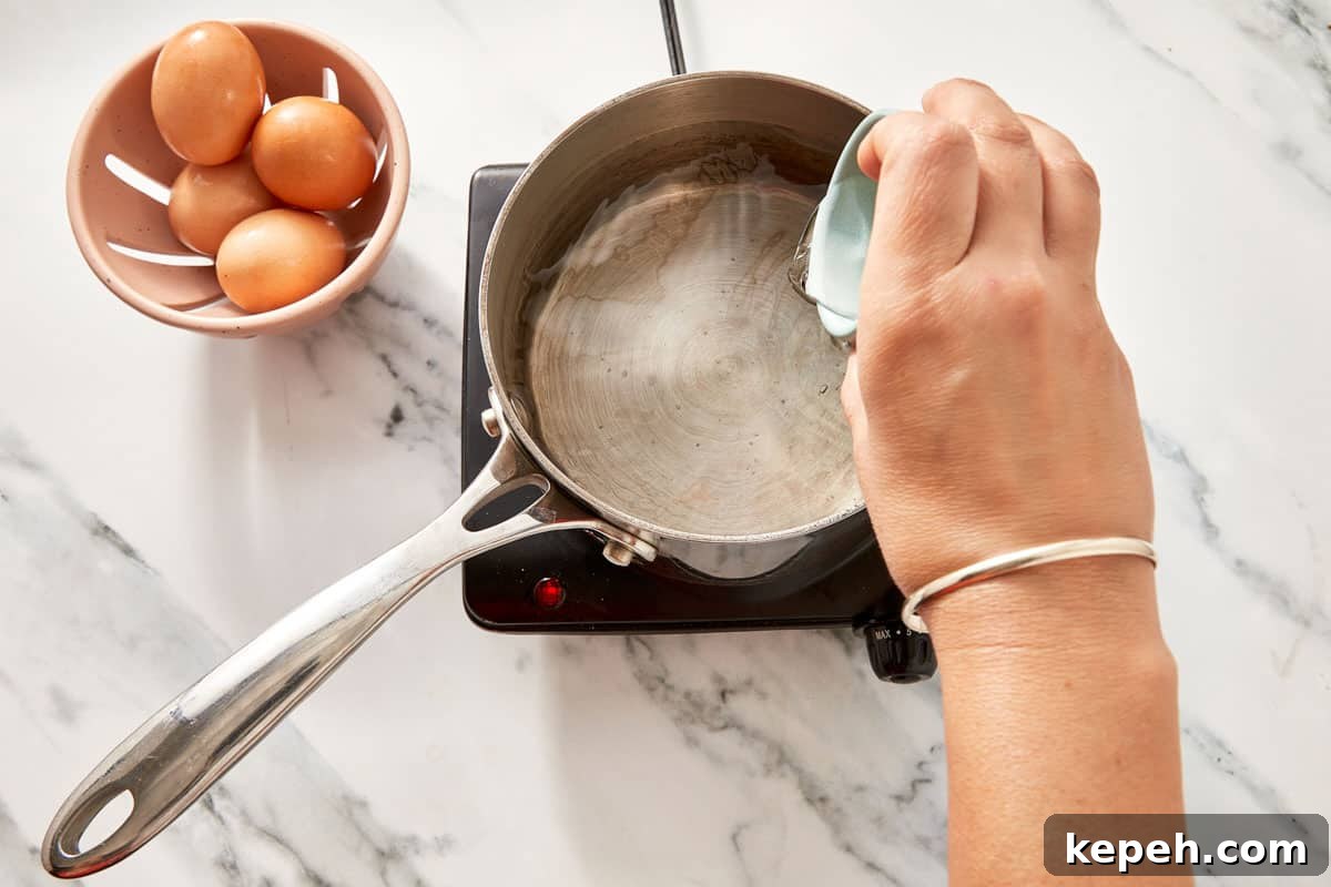 A hand holding a ramekin over a saucepan with gently simmering water and a spoon creating a whirlpool.