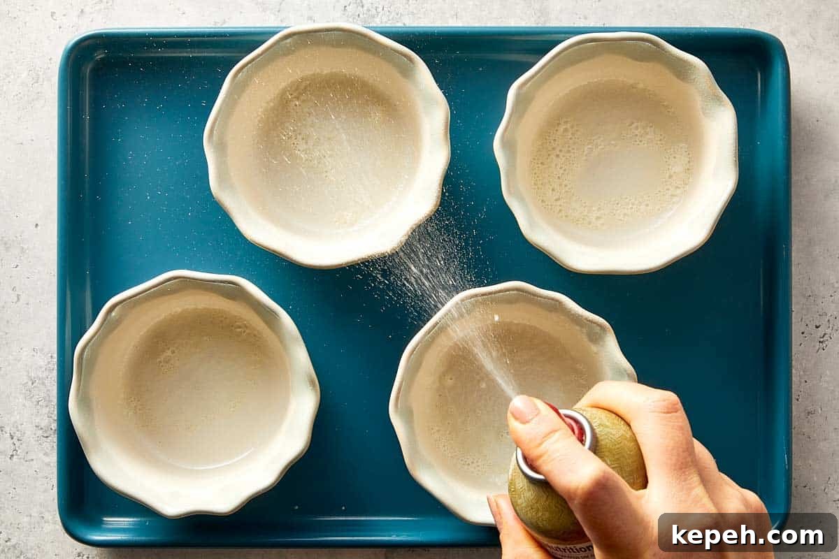 overview of two small bowls being spray with non stick cooking spray.