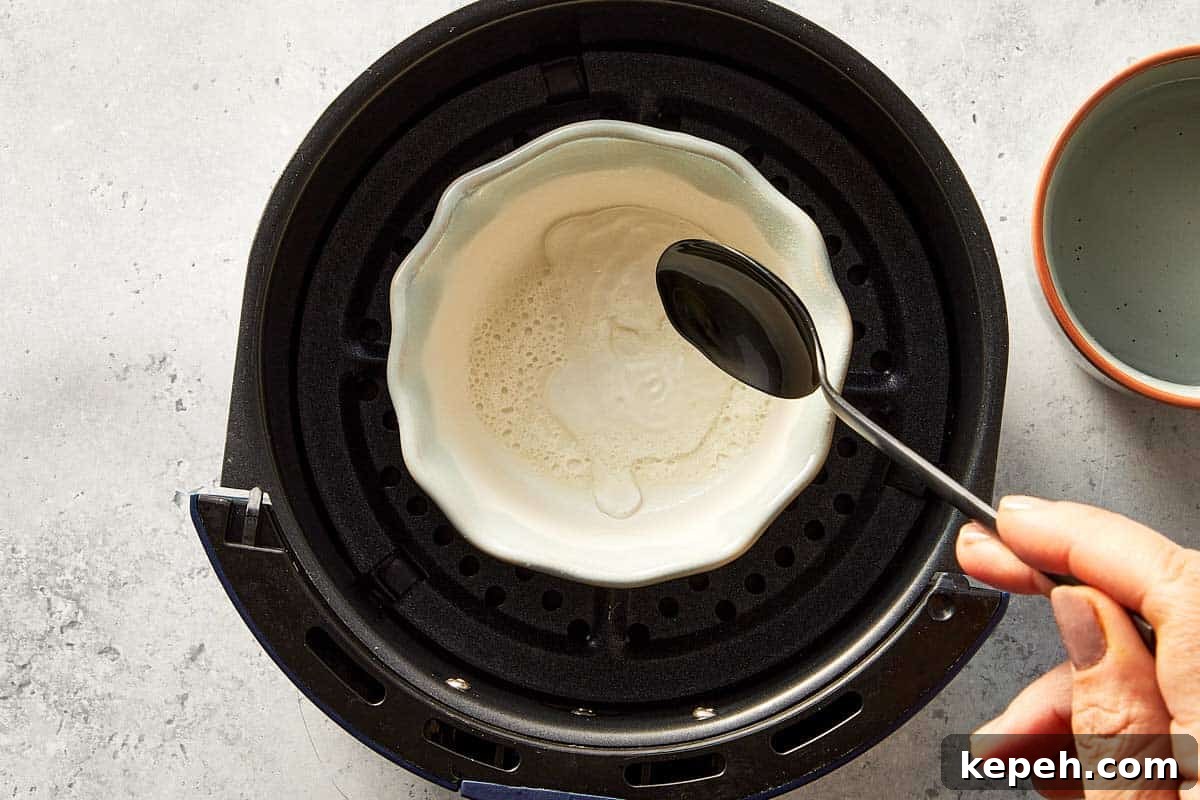 Top overview of a hand pouring 2 tbsp of water in a ramekin