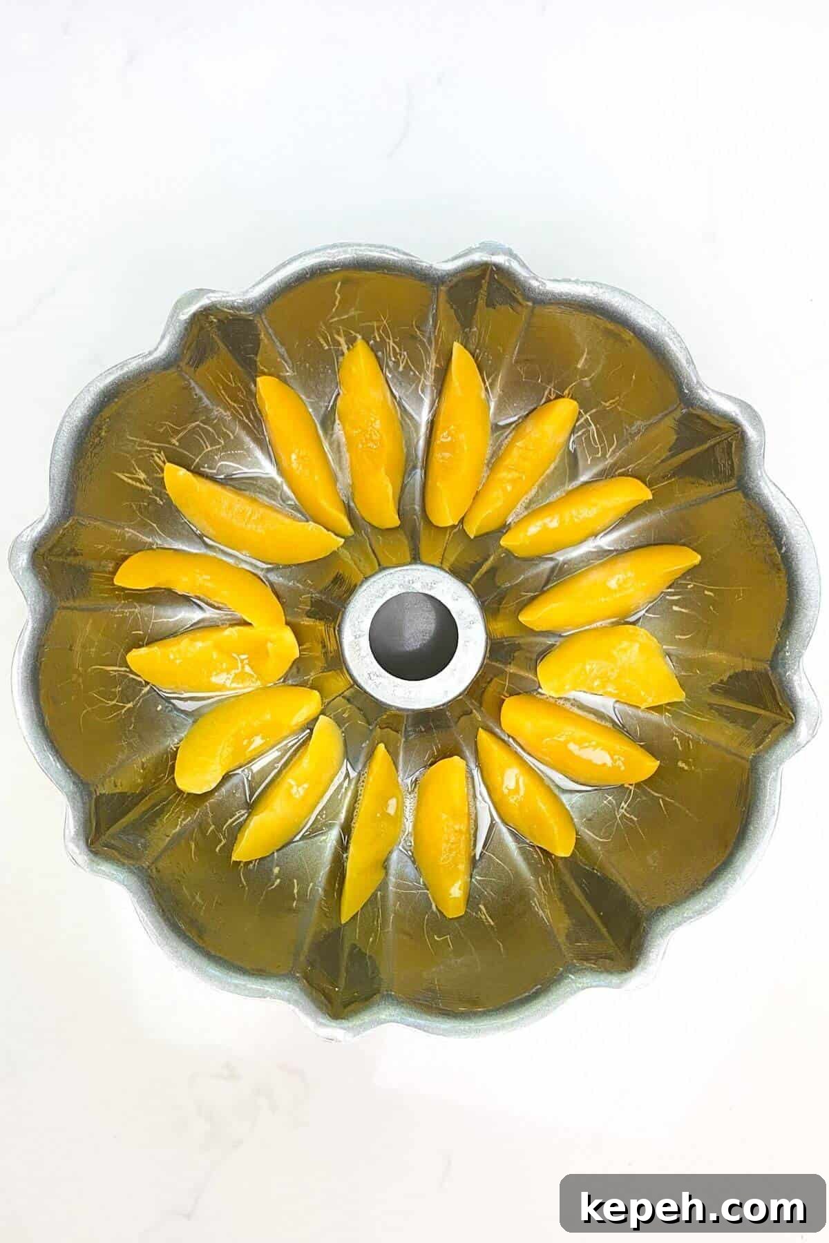 Sliced peaches lined along the bottom of a bundt pan.