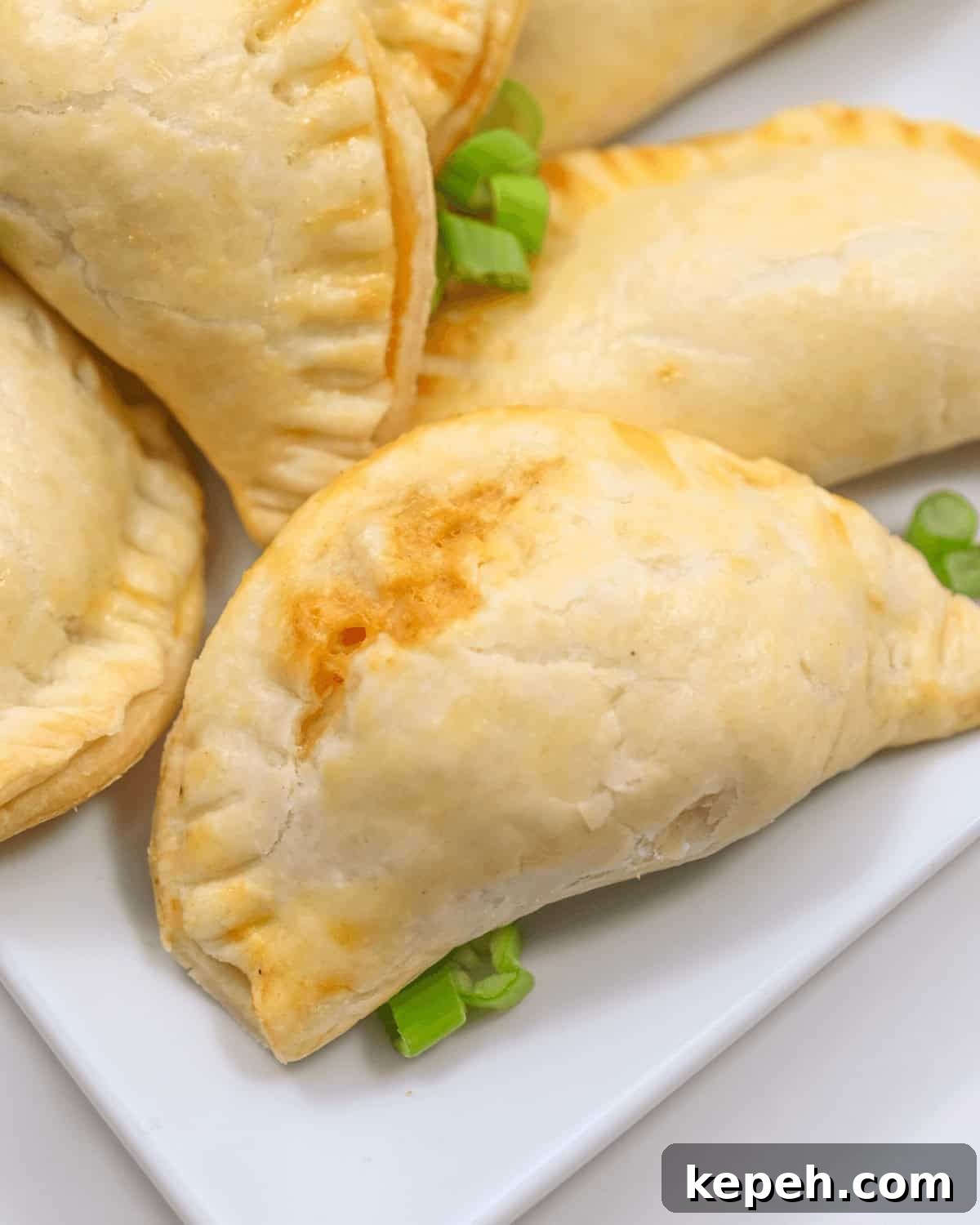 Buffalo Chicken Empanadas Recipe: Crispy Spicy Stuffed Turnovers 2 A plate of buffalo chicken empanadas on a white plate.