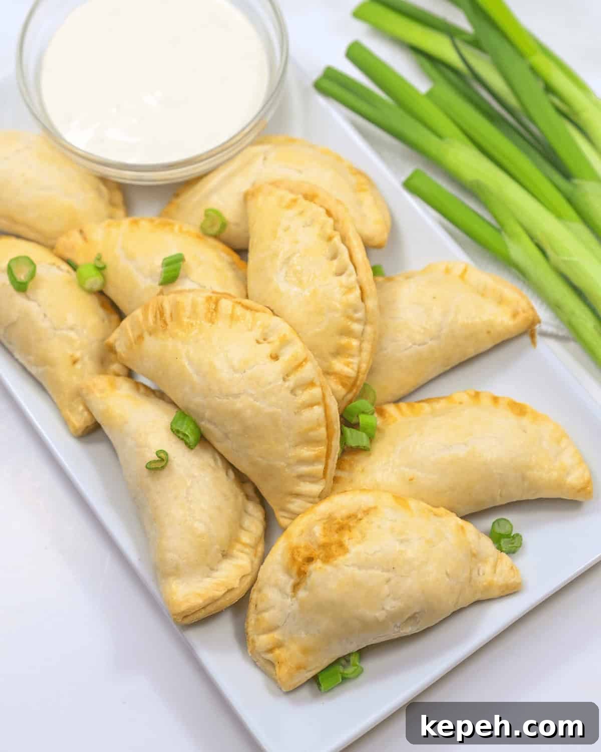 Buffalo Chicken Empanadas Recipe: Crispy Spicy Stuffed Turnovers 7 Chicken empanadas served on a white plate with a dip.
