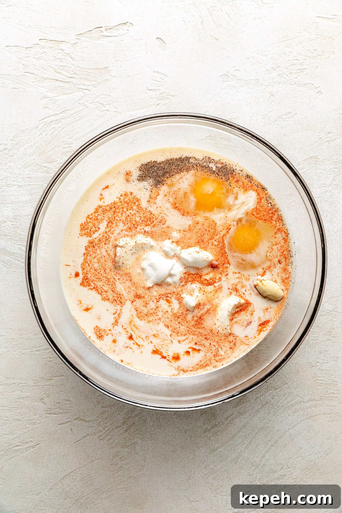 Eggs, milk, spices, and sour cream in a bowl.