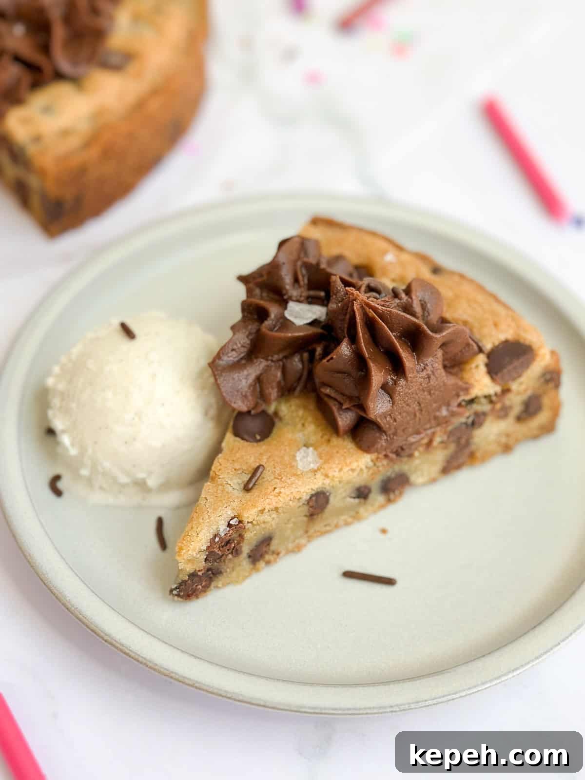 Chocolate Chip Cookie Cake Recipe: Soft, Gooey, Rich 12 a single piece of the cookie cake on a plate with a scoop of ice cream.