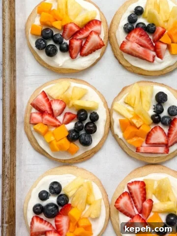 a few of the sugar cookie fruit pizzas on a cookie sheet.