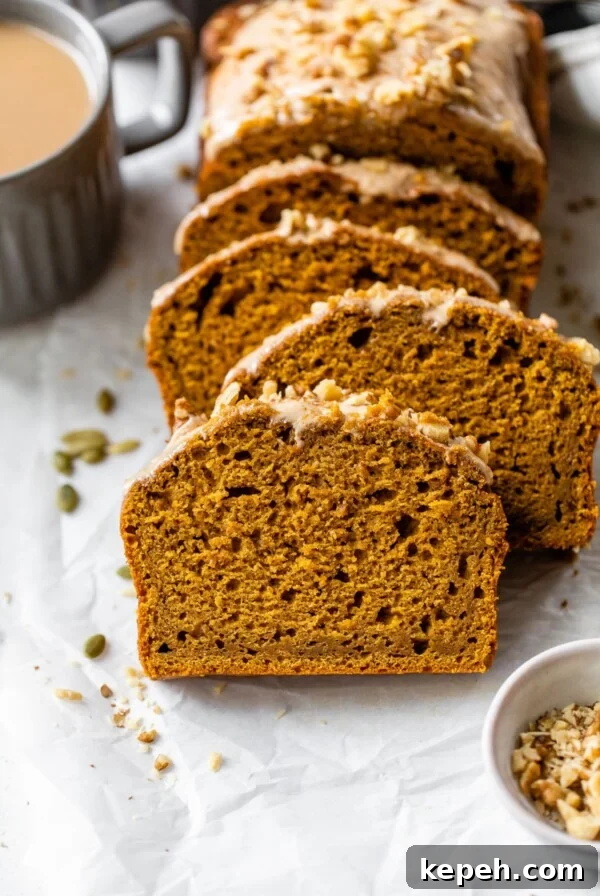 sliced pumpkin bread on parchment paper beside a mug of coffee