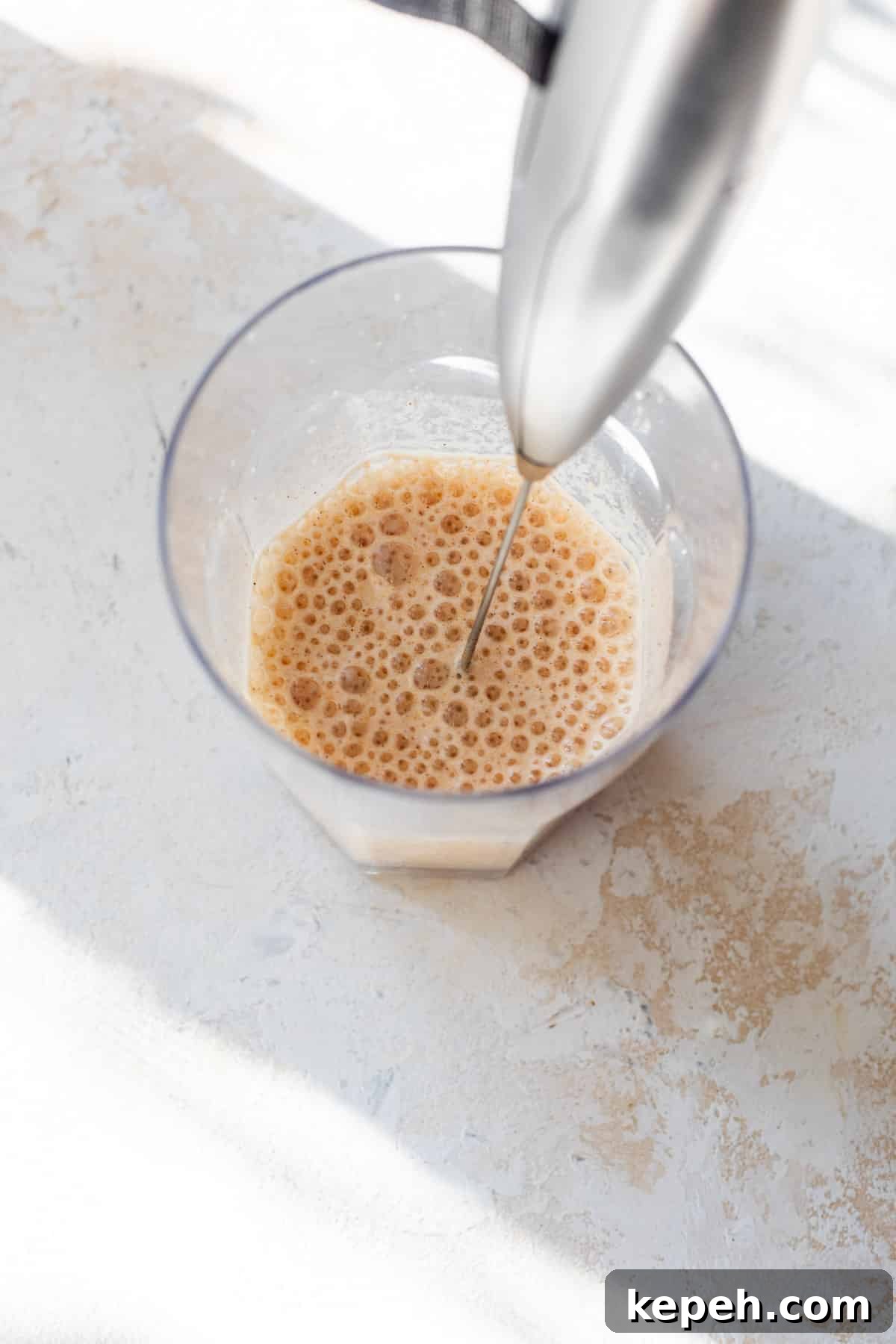 How to Make Pumpkin Cream Cold Brew 6 using a milk frother to make frothy pumpkin creamer in a glass.