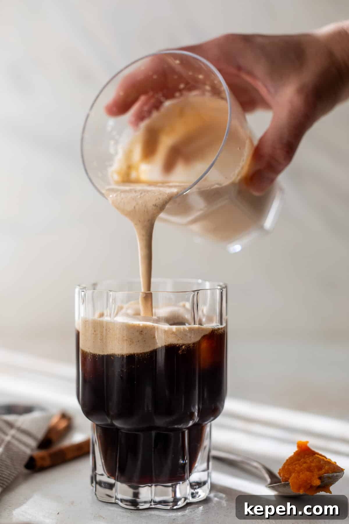 How to Make Pumpkin Cream Cold Brew 7 a hand pouring pumpkin creamer into a glass of cold brew.