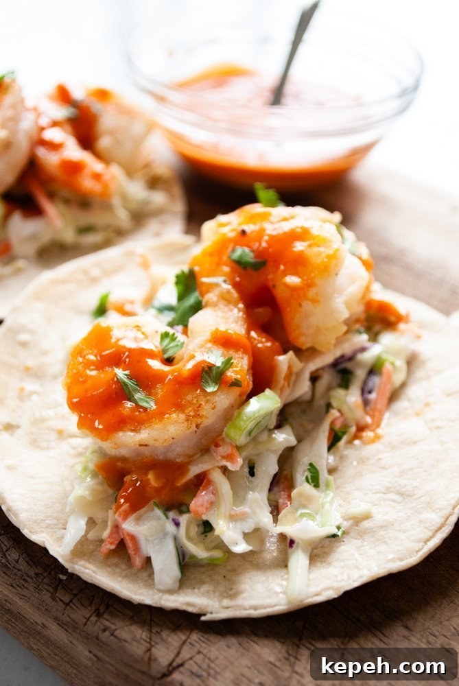 Crispy Bang Bang Shrimp Tacos with Creamy Slaw 5 A close up shot of a shrimp taco with bang bang sauce.