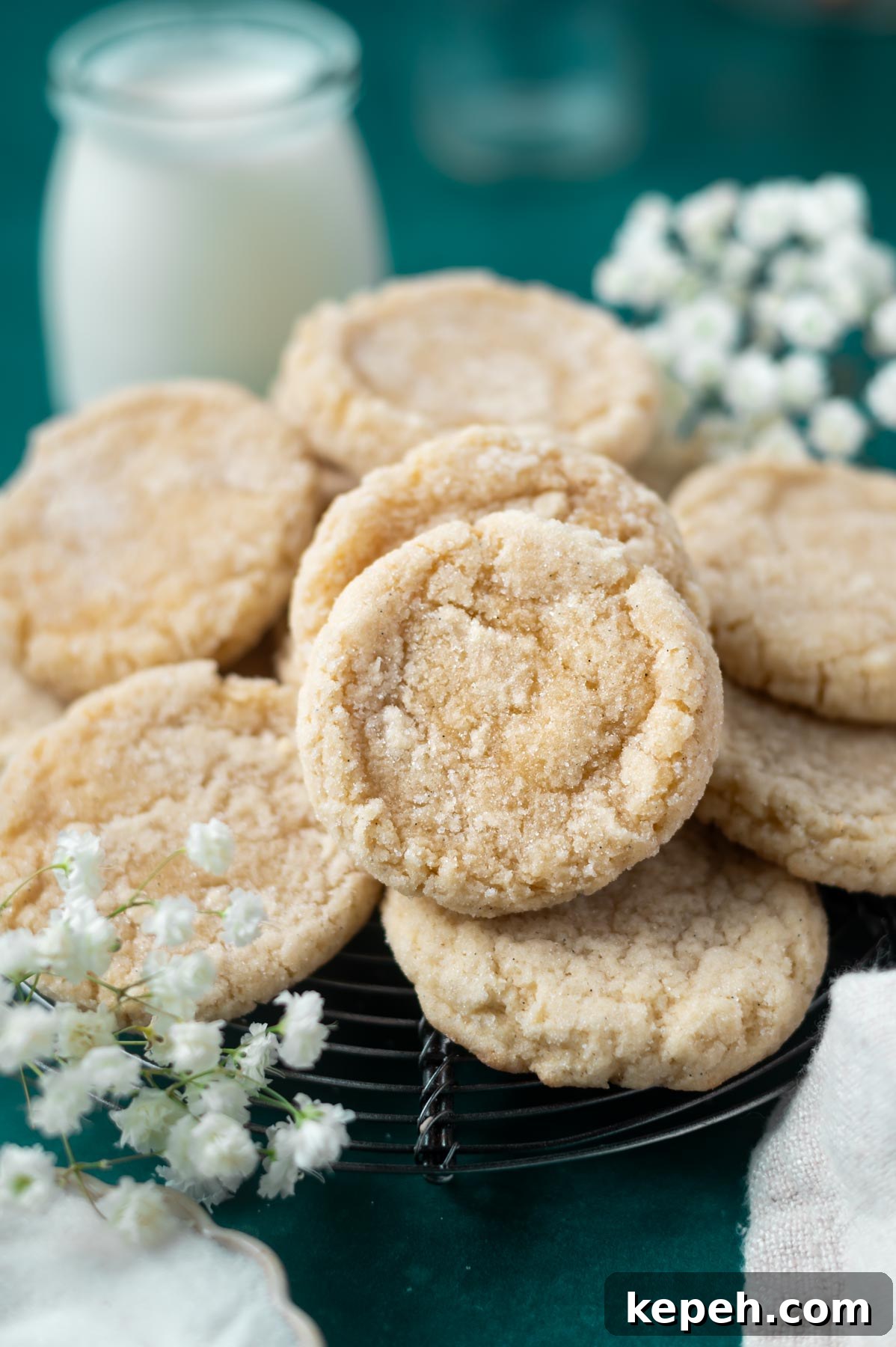 Classic Vanilla Bean Cookies with Old Fashioned Flavor 2 vanilla bean sugar cookies on a cooling rack with fresh flowers and milk in the background
