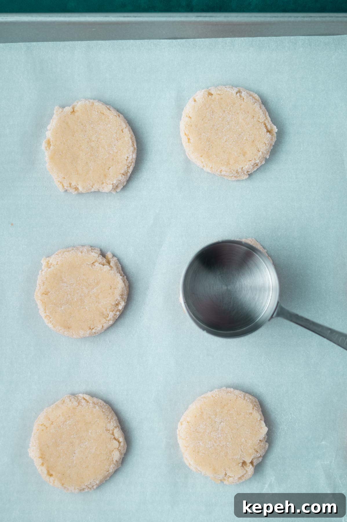 Classic Vanilla Bean Cookies with Old Fashioned Flavor 9 measuring cup flattening cookie dough balls on a parchment lined baking pan