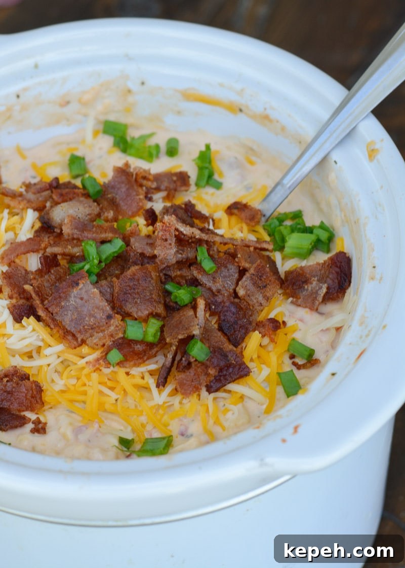 Creamy Slow Cooker Corn Dip 7 a small white slow cooker filled with creamy corn dip, topped with crunchy bacon and shredded cheddar cheese