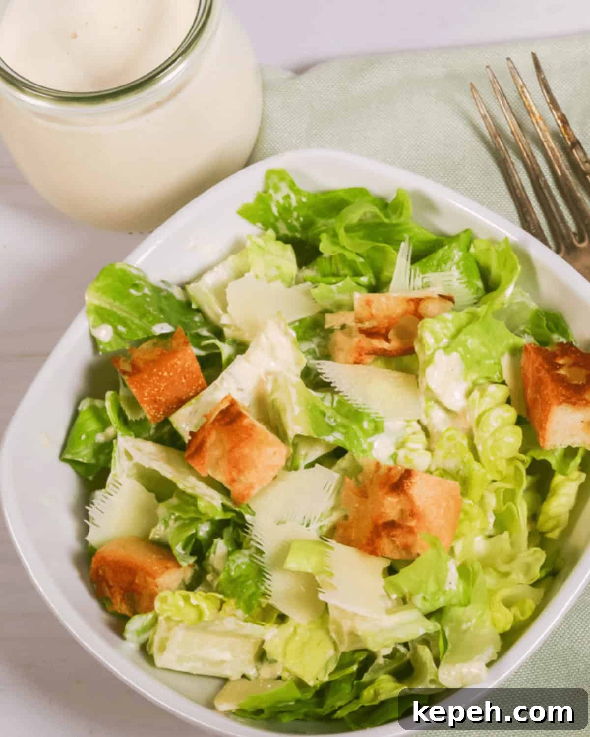 Classic Caesar Salad with Homemade Dressing 6 A fresh best caesar salad with croutons and shaved parmesan cheese, accompanied by a jar of dressing.