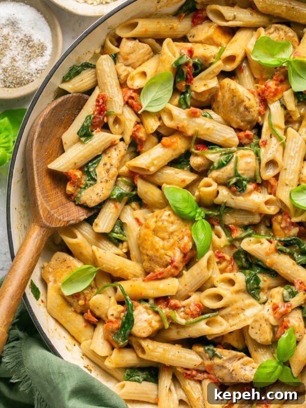 Marry me chicken pasta in a skillet with a wooden spoon