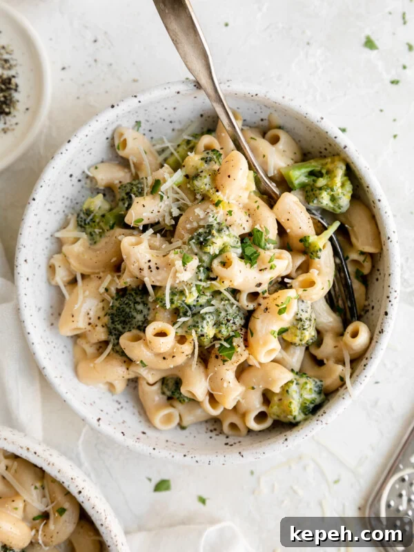 One Pot Gluten Free Broccoli Mac and Cheese in a bowl with parmesan cheese and a spoon
