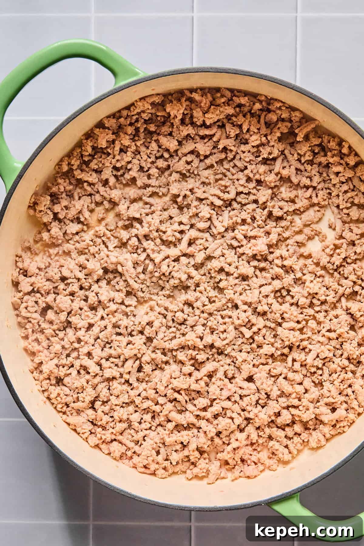Ground turkey cooking in olive oil in a large skillet, broken up and browned.