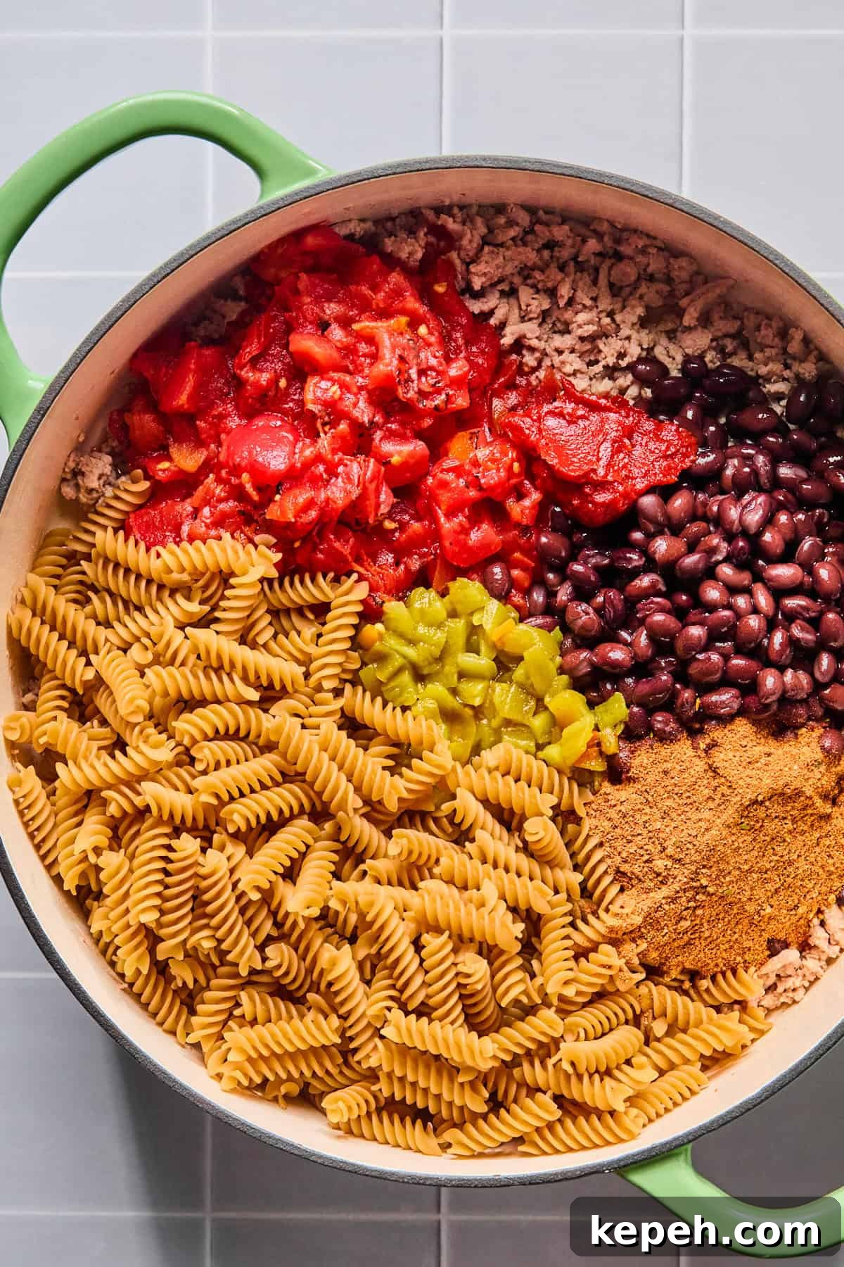 Taco seasoning, tomato paste, diced tomatoes, green chiles, black beans, and pasta in the skillet.