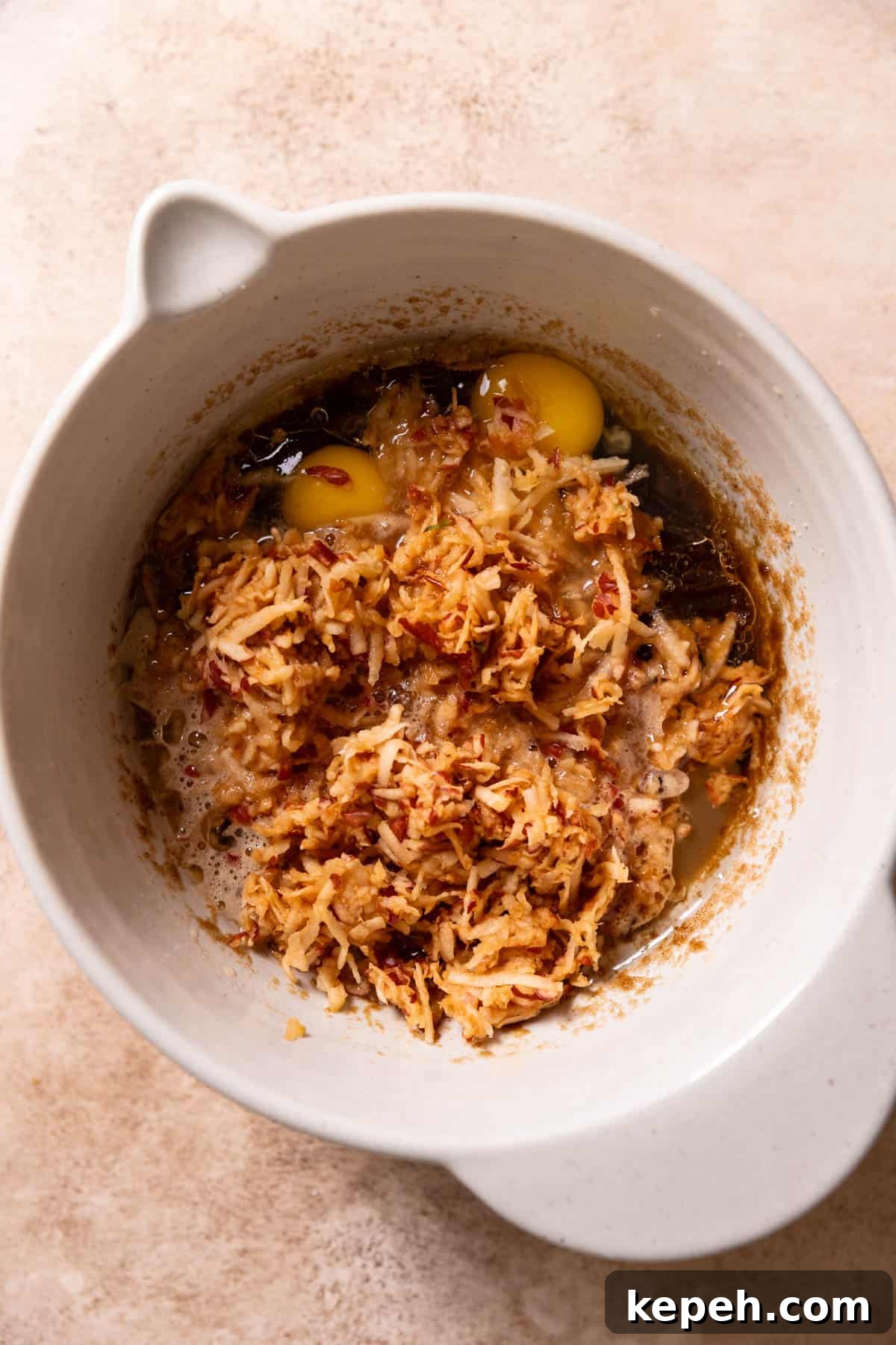 A mixing bowl with the wet ingredients, shredded apples, and apple juice before mixing.