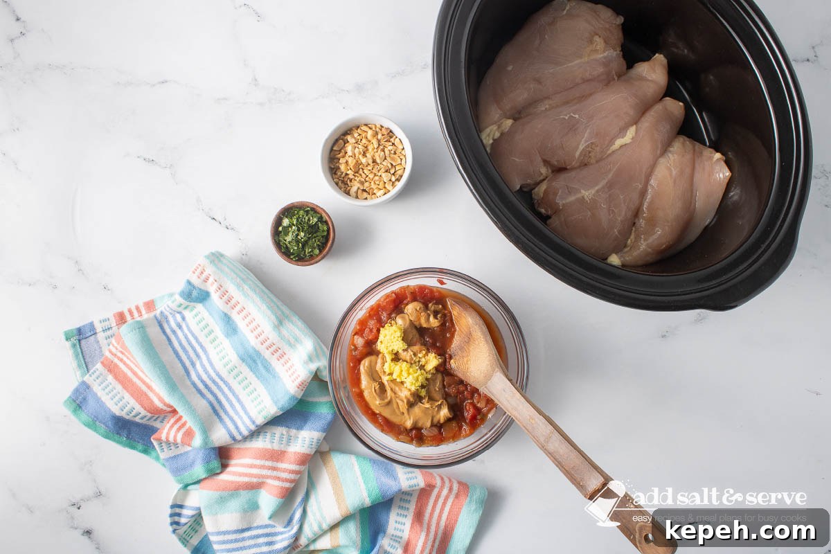 Slow Cooker Thai Peanut Chicken Recipe 5 Uncooked chicken breasts in a slow cooker and small bowls of chopped peanuts and cilantro around a bowl of peanut butter, salsa, soy sauce, grated ginger, and lime juice before mixing.